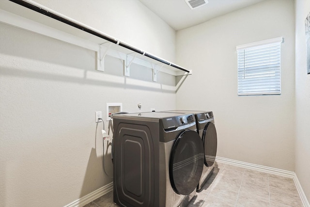 clothes washing area with light tile patterned floors and independent washer and dryer