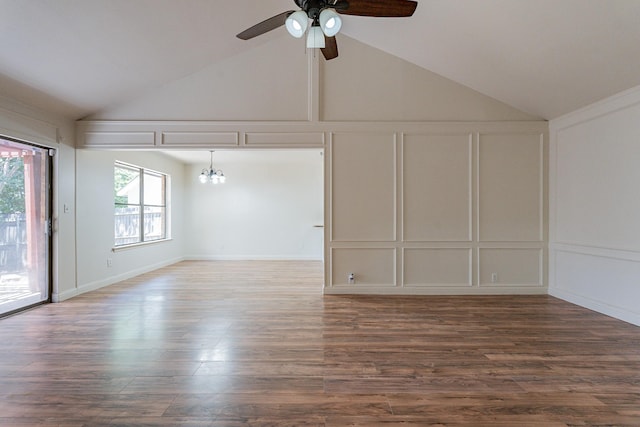 spare room featuring ceiling fan with notable chandelier, high vaulted ceiling, dark wood-style flooring, and a decorative wall