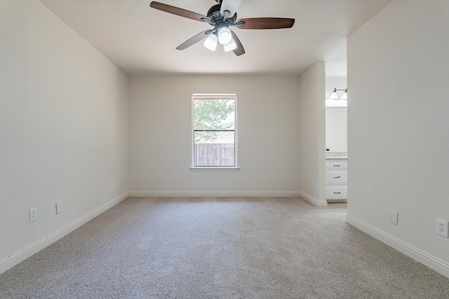 unfurnished room with a ceiling fan, light colored carpet, and baseboards