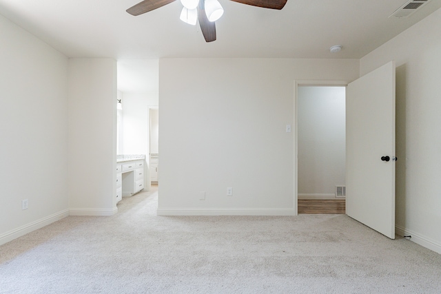 unfurnished bedroom featuring light carpet, connected bathroom, and ceiling fan