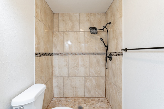 bathroom with toilet and a tile shower