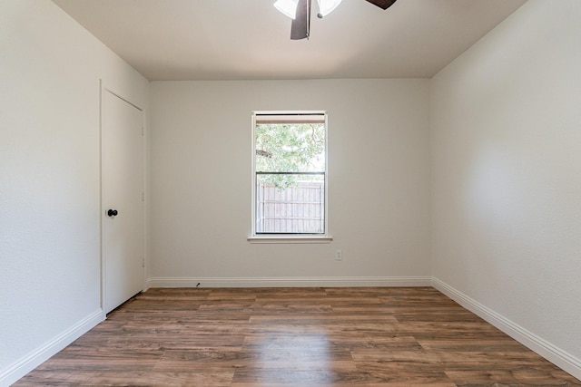 empty room featuring ceiling fan, dark wood finished floors, and baseboards