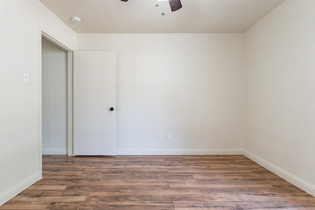 spare room featuring a ceiling fan, baseboards, and dark wood-style flooring