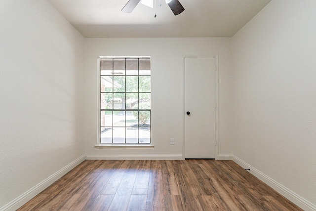 unfurnished room featuring dark wood finished floors, a ceiling fan, and baseboards