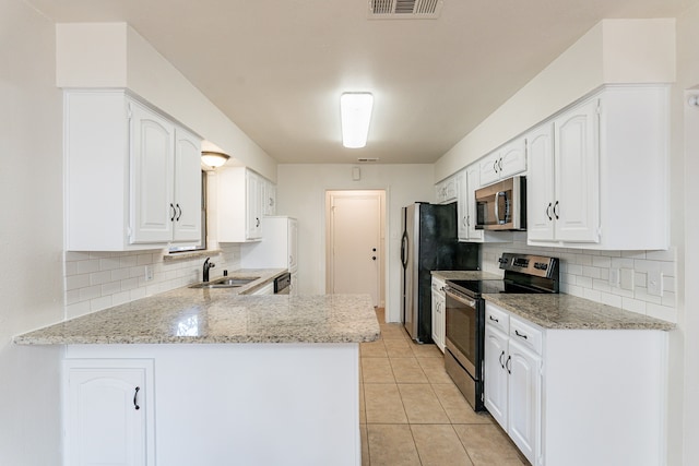 kitchen with stainless steel appliances, sink, kitchen peninsula, light tile patterned floors, and white cabinetry