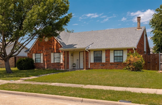 view of front of property featuring a front yard, fence, and brick siding