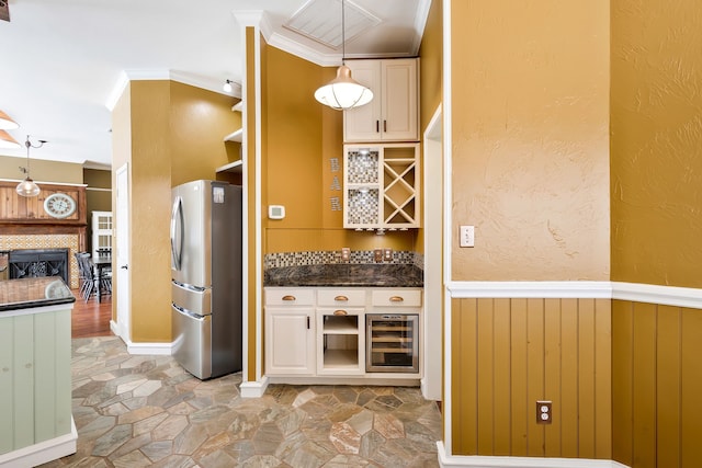 kitchen with hanging light fixtures, ornamental molding, stainless steel fridge, and beverage cooler