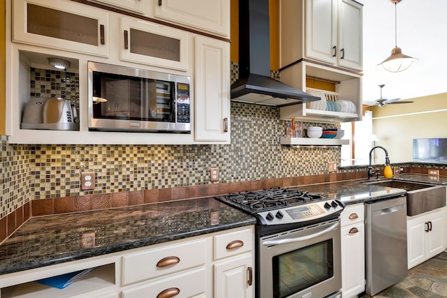 kitchen featuring wall chimney exhaust hood, tasteful backsplash, hanging light fixtures, ceiling fan, and stainless steel appliances