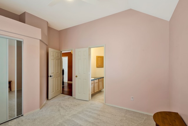 unfurnished bedroom with ensuite bathroom, high vaulted ceiling, light carpet, a closet, and ceiling fan