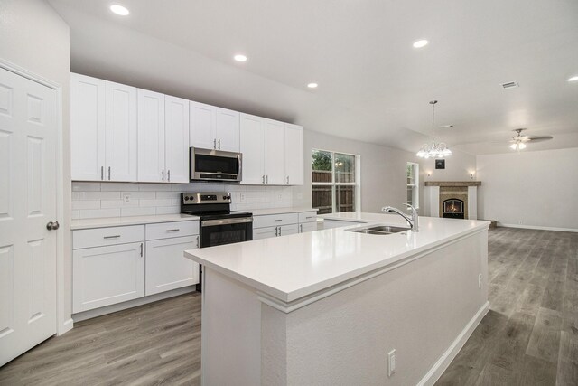 kitchen with appliances with stainless steel finishes, light hardwood / wood-style flooring, a center island with sink, sink, and decorative backsplash