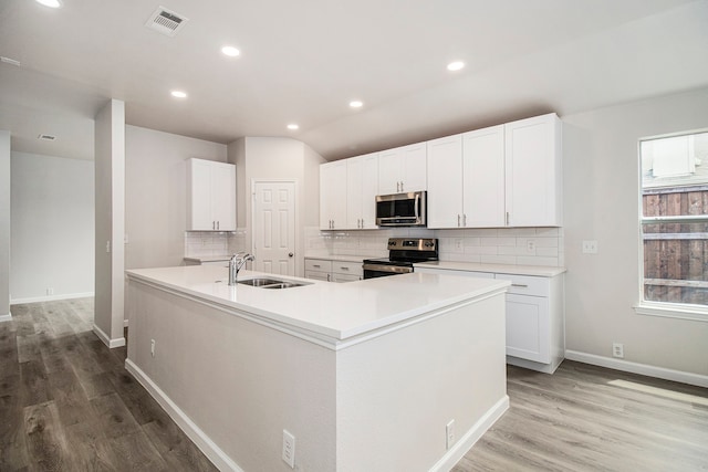 kitchen featuring appliances with stainless steel finishes, light hardwood / wood-style flooring, sink, decorative backsplash, and white cabinetry