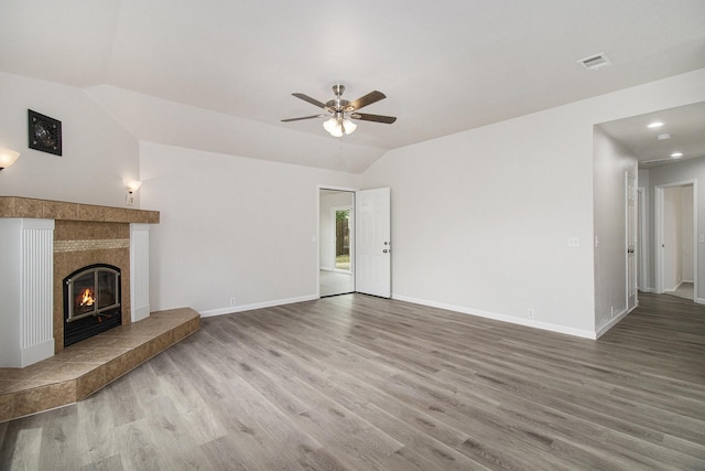 unfurnished living room with a fireplace, vaulted ceiling, light wood-type flooring, and ceiling fan