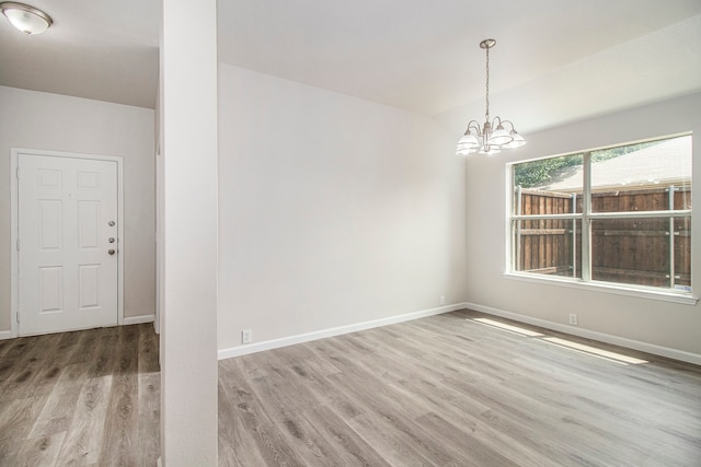 empty room featuring an inviting chandelier and hardwood / wood-style floors