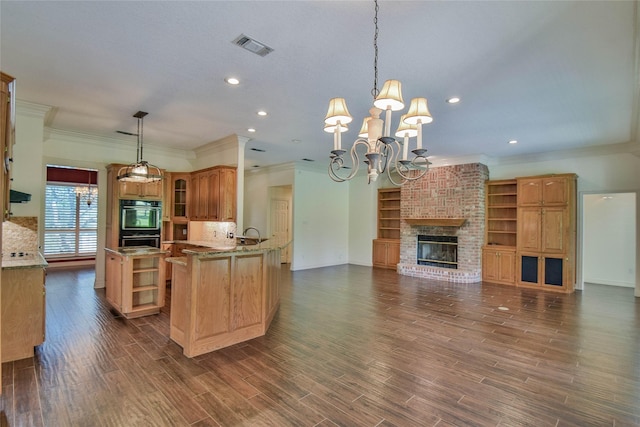 kitchen with dark hardwood / wood-style floors, hanging light fixtures, a notable chandelier, kitchen peninsula, and a brick fireplace