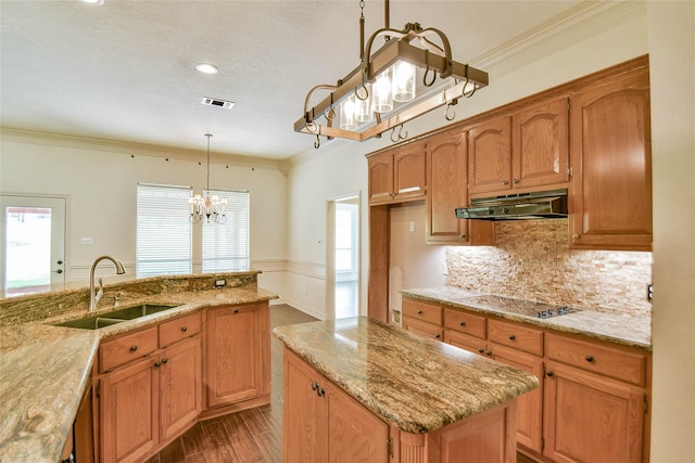 kitchen with sink, hanging light fixtures, ornamental molding, black electric stovetop, and light stone countertops