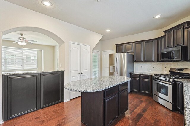 kitchen featuring a kitchen island, appliances with stainless steel finishes, dark wood-type flooring, and tasteful backsplash