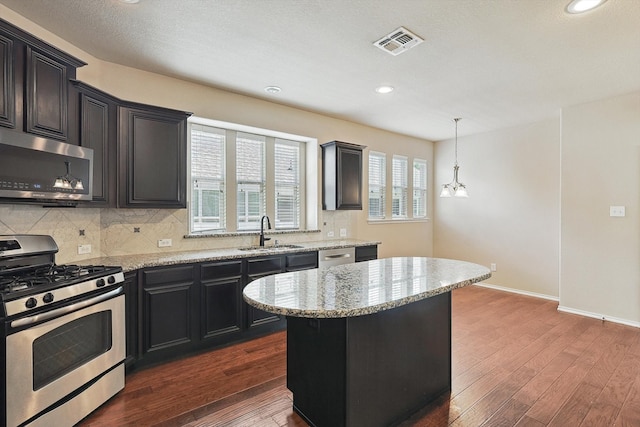 kitchen with stainless steel appliances, wood-type flooring, a center island, and a wealth of natural light