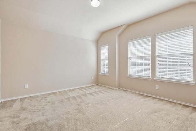 carpeted empty room with lofted ceiling