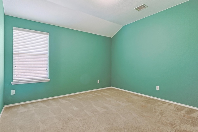 empty room with carpet floors and vaulted ceiling