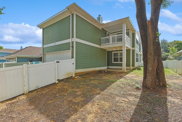 back of house featuring a balcony and a garage