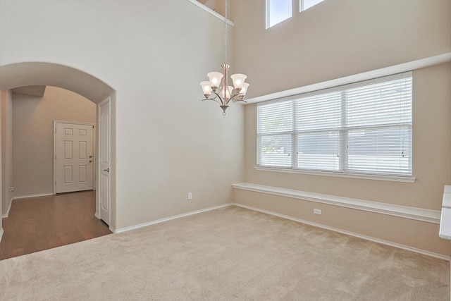 spare room featuring a notable chandelier, carpet, and plenty of natural light