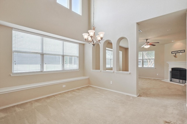 unfurnished room featuring ceiling fan with notable chandelier, carpet flooring, and a healthy amount of sunlight