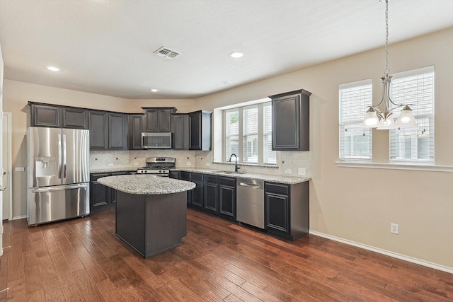 kitchen featuring a center island, appliances with stainless steel finishes, dark wood-type flooring, and backsplash