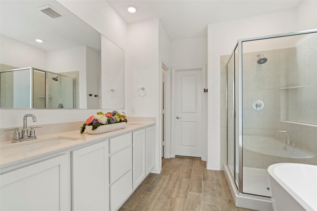 bathroom featuring shower with separate bathtub, wood-type flooring, and dual bowl vanity