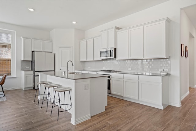 kitchen with white cabinets, appliances with stainless steel finishes, sink, and an island with sink