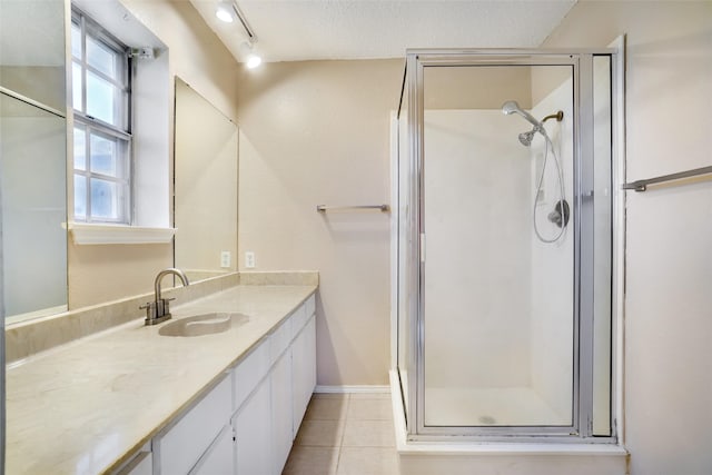 bathroom featuring vanity, walk in shower, a textured ceiling, tile patterned flooring, and track lighting