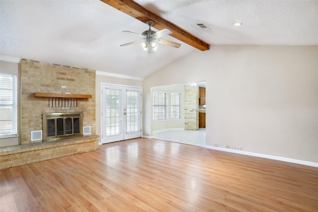 unfurnished living room featuring light tile patterned floors, ceiling fan, vaulted ceiling with beams, a textured ceiling, and a brick fireplace