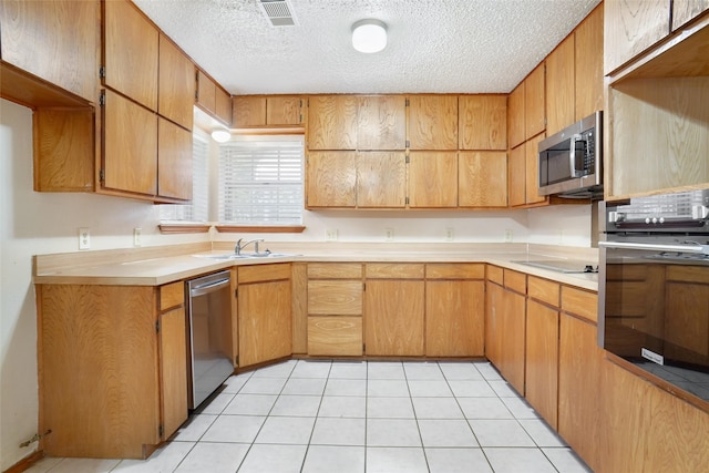 kitchen with sink, appliances with stainless steel finishes, light tile patterned floors, and a textured ceiling