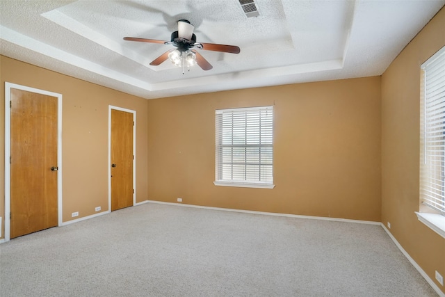 unfurnished room featuring carpet floors, a textured ceiling, ceiling fan, and a tray ceiling