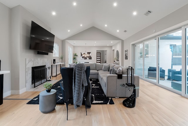 living room featuring a premium fireplace, light hardwood / wood-style flooring, and high vaulted ceiling