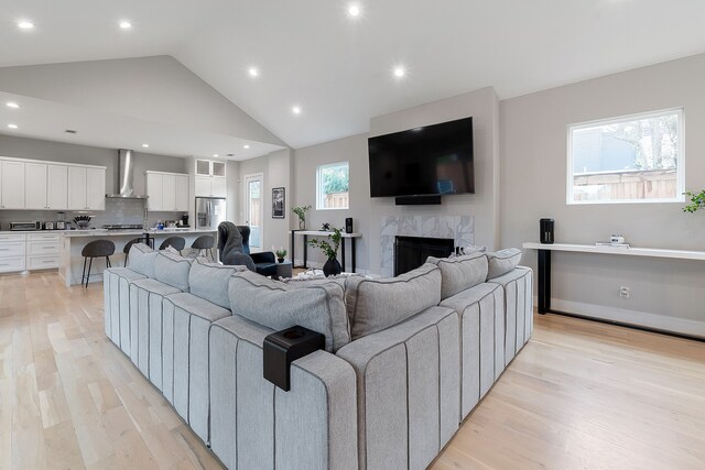 living room featuring light hardwood / wood-style floors, high vaulted ceiling, and a fireplace