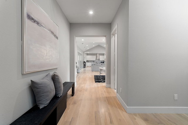 hall with lofted ceiling and light hardwood / wood-style floors