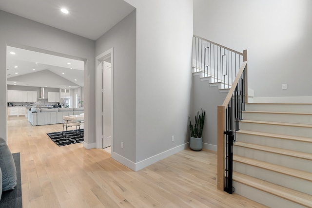 stairs featuring lofted ceiling and wood-type flooring