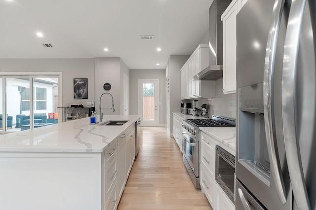 kitchen with appliances with stainless steel finishes, white cabinetry, a kitchen island with sink, and sink