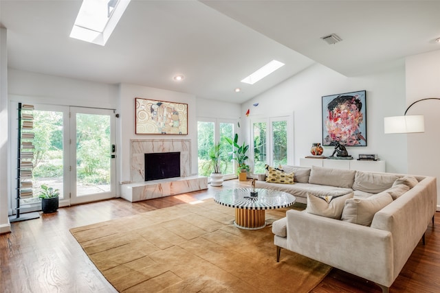 living room featuring a fireplace, a healthy amount of sunlight, light wood-type flooring, and lofted ceiling with skylight