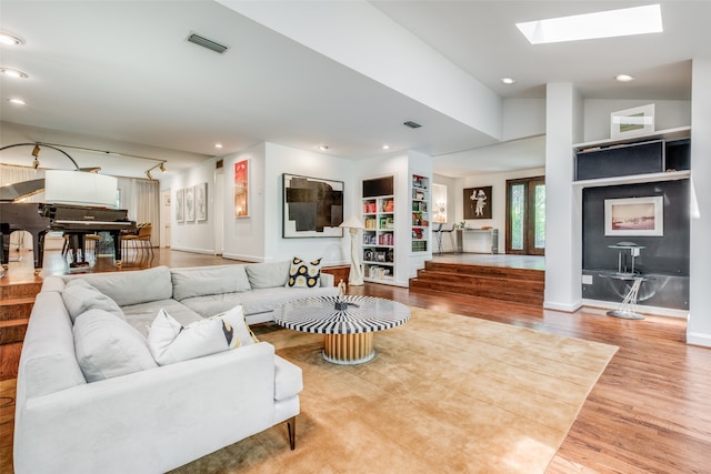 living room with a skylight and light hardwood / wood-style flooring