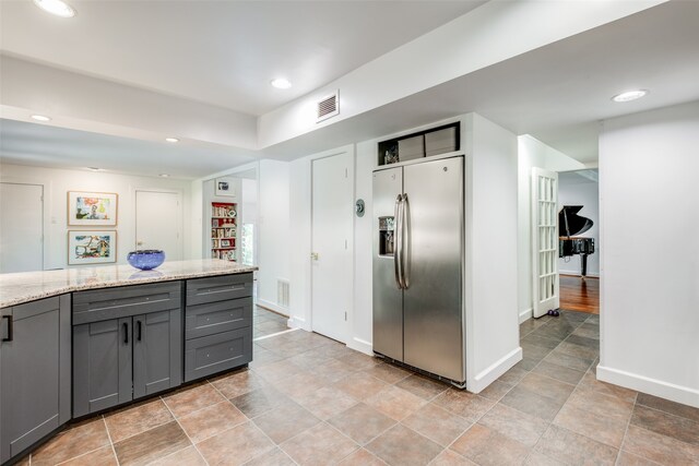 kitchen with light stone countertops, gray cabinets, stainless steel fridge, and light tile patterned floors