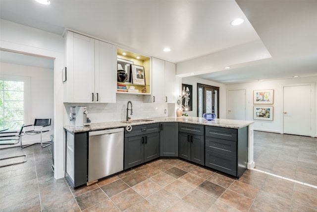 kitchen with kitchen peninsula, white cabinetry, light stone countertops, tile patterned floors, and dishwasher