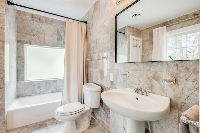 full bathroom featuring sink, tile walls, shower / tub combo with curtain, toilet, and tile patterned floors