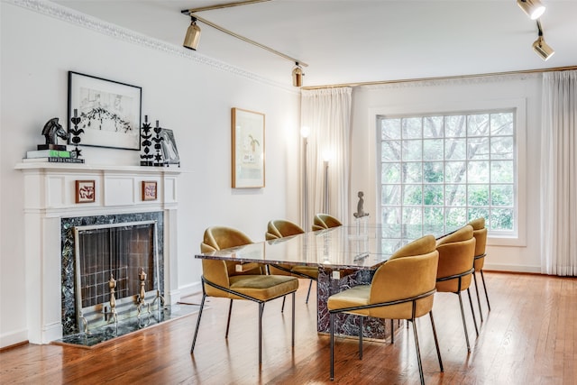 dining space featuring a fireplace, rail lighting, and hardwood / wood-style floors