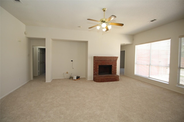 unfurnished living room with light carpet, a brick fireplace, and ceiling fan