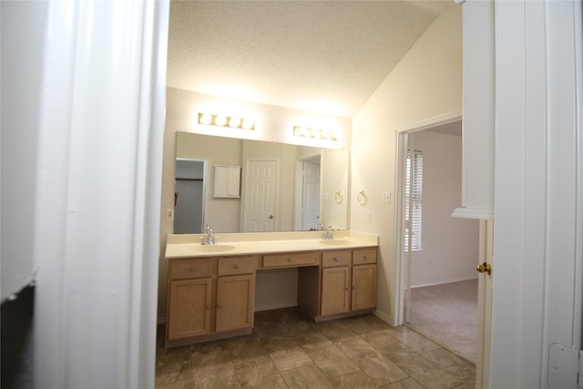 bathroom featuring lofted ceiling, vanity, and a textured ceiling