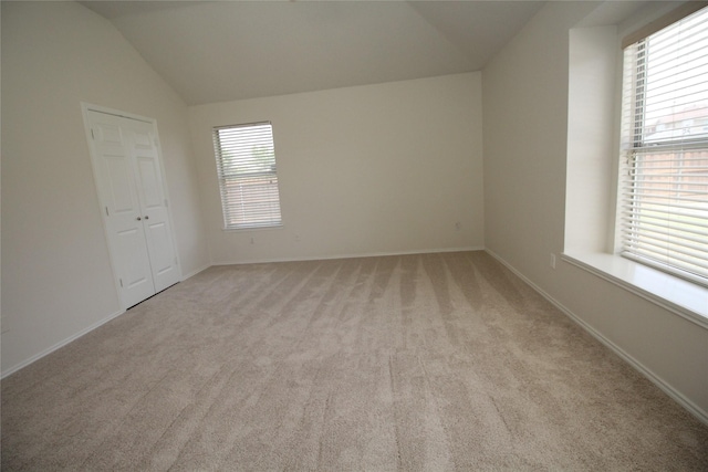 unfurnished room featuring light carpet, vaulted ceiling, and a healthy amount of sunlight