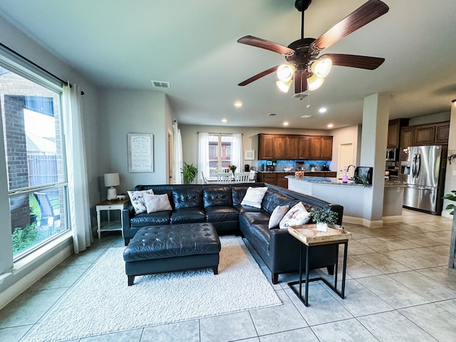 living room with light tile patterned flooring, ceiling fan, and a wealth of natural light