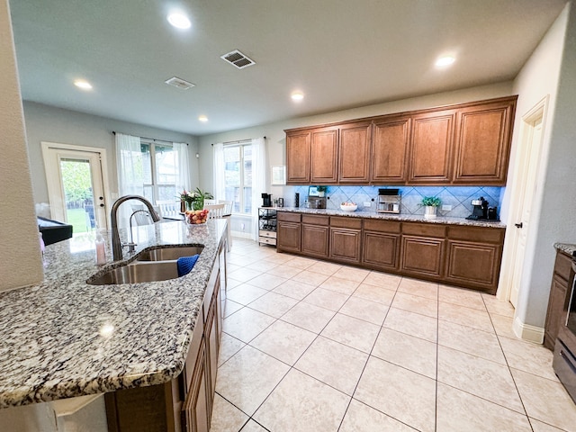 kitchen featuring a healthy amount of sunlight, sink, light stone counters, and backsplash