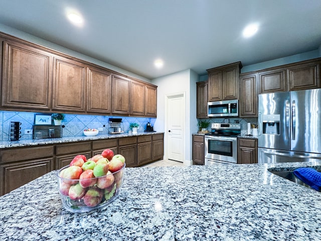 kitchen featuring light stone countertops, tasteful backsplash, and stainless steel appliances